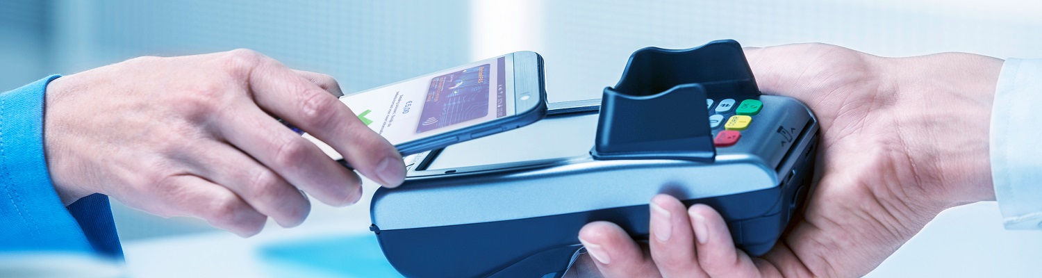 Klant houdt een smartphone tegen een betaalterminal terwijl een medewerker het pinapparaat vasthoudt, tijdens een contactloze mobiele betaling.