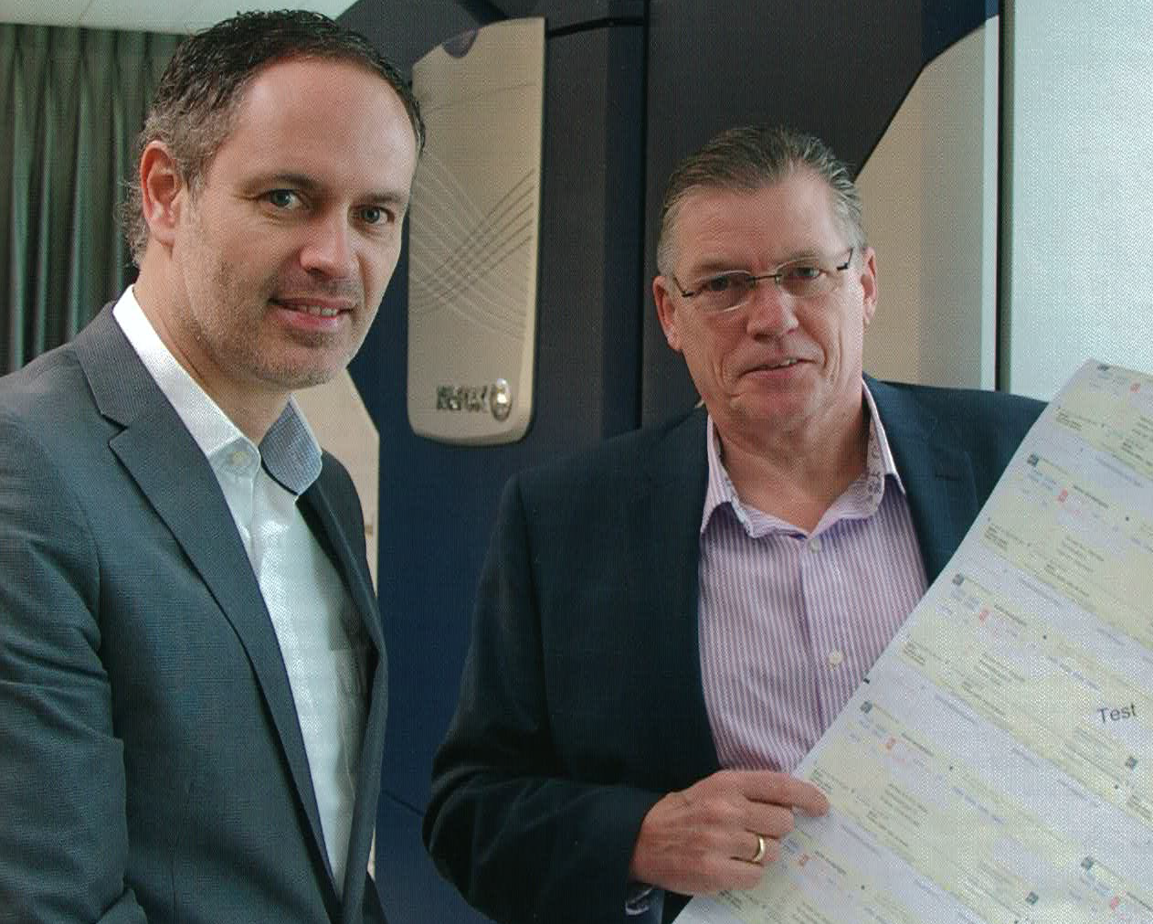 Two business professionals show a sheet of printed payment slips in an office environment, as an example of paper requests-to-pay.