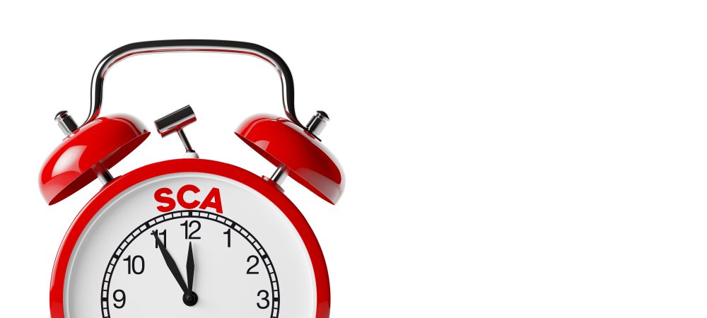 Red alarm clock with the text 'SCA' on the dial, which emphasizes the importance of timely implementation of strong customer authentication in the payments.