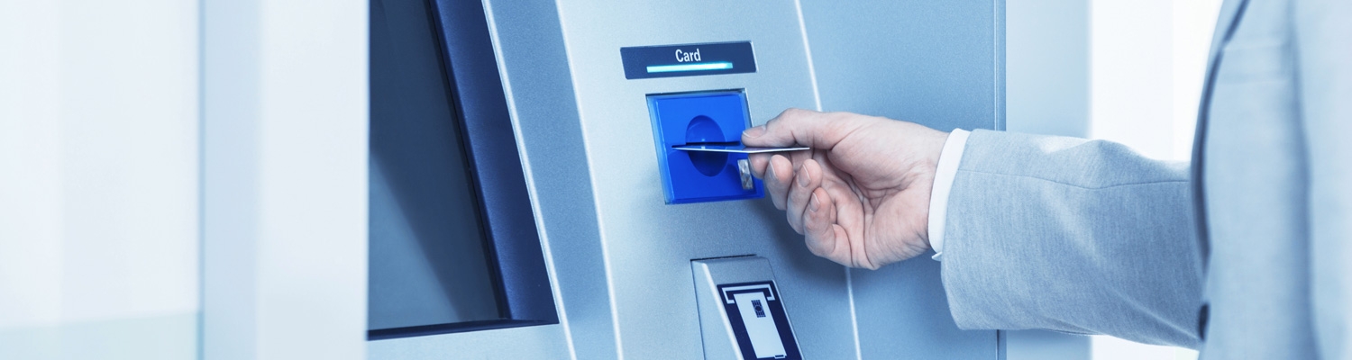Hand inserts a debit card into a payment terminal, initiating a card transaction in a quiet, business environment.
