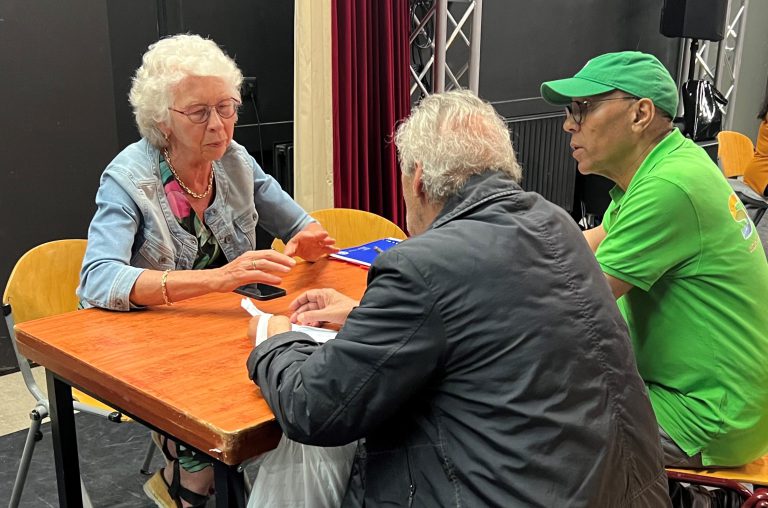 Volunteer assists two visitors at the bank information point at Afrikaanderplein in Rotterdam.