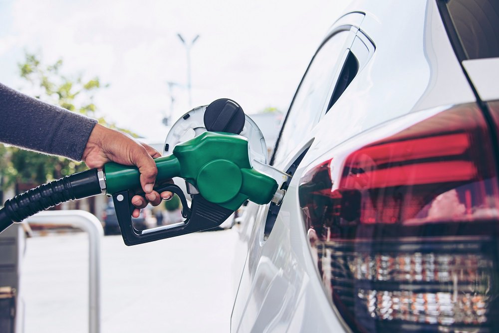 Hand fills a car with fuel at a gas station, as part of an everyday payment and settlement process on the road.