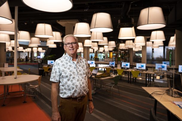 Retired bank employee stands in a library computer area during the ‘Getting to grips with digital banking’ pilot.