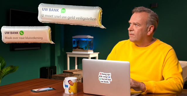 Man sits behind a laptop and looks alertly at suspicious messages calling on behalf of a bank to secure money, in a homely working environment.