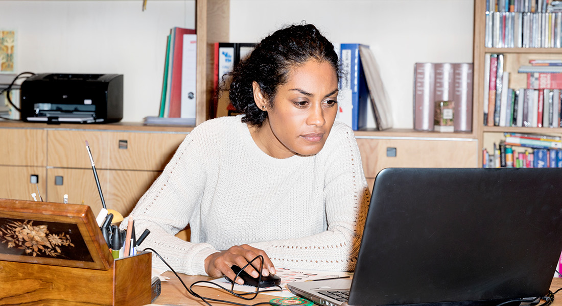 Woman works concentrated behind a laptop in a homely office and pays attention to safe internet use and online banking.