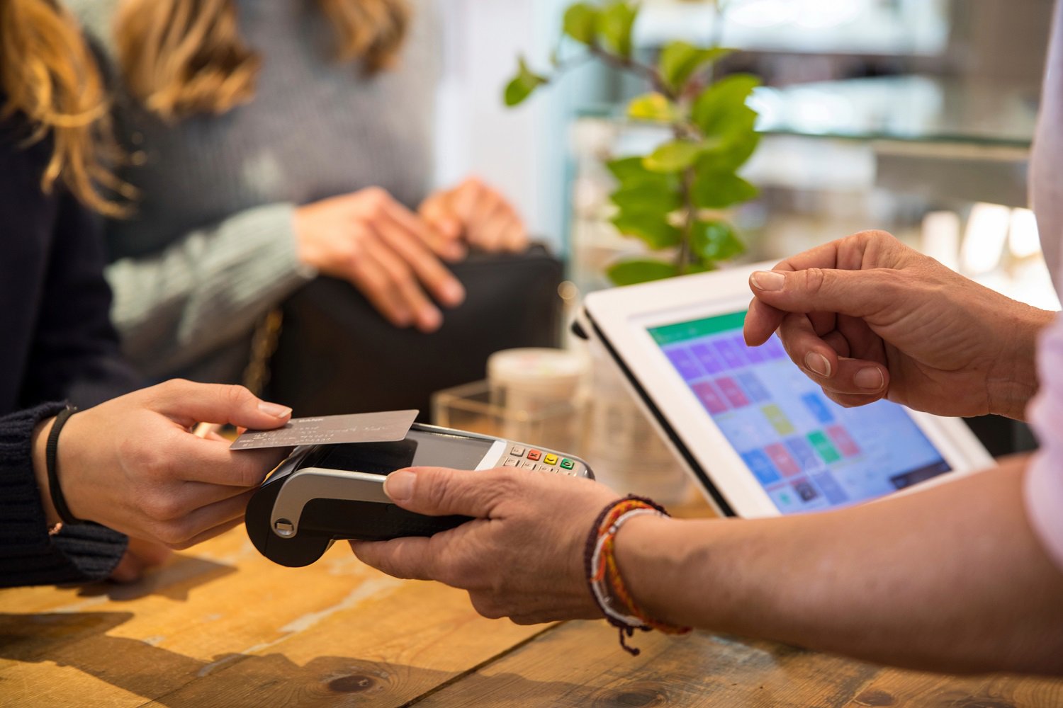 Customer pays at the point-of-sale by holding a debit card against a POS terminal while the associate completes the payment in a retail environment.