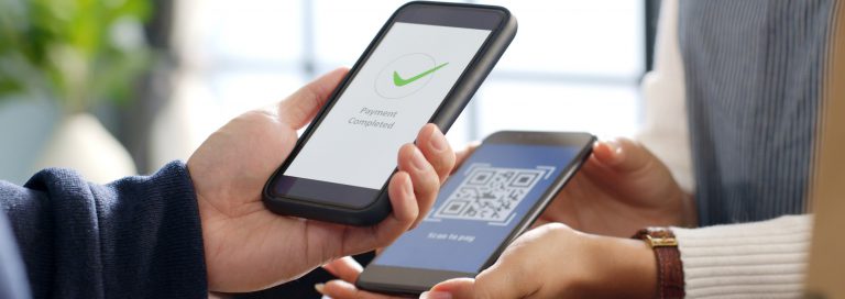 Person scanning a QR code with a smartphone to make a payment.