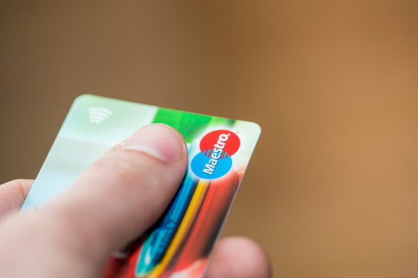 Hand holding a Maestro debit card, illustrating the phase-out of Maestro from mid-2023.
