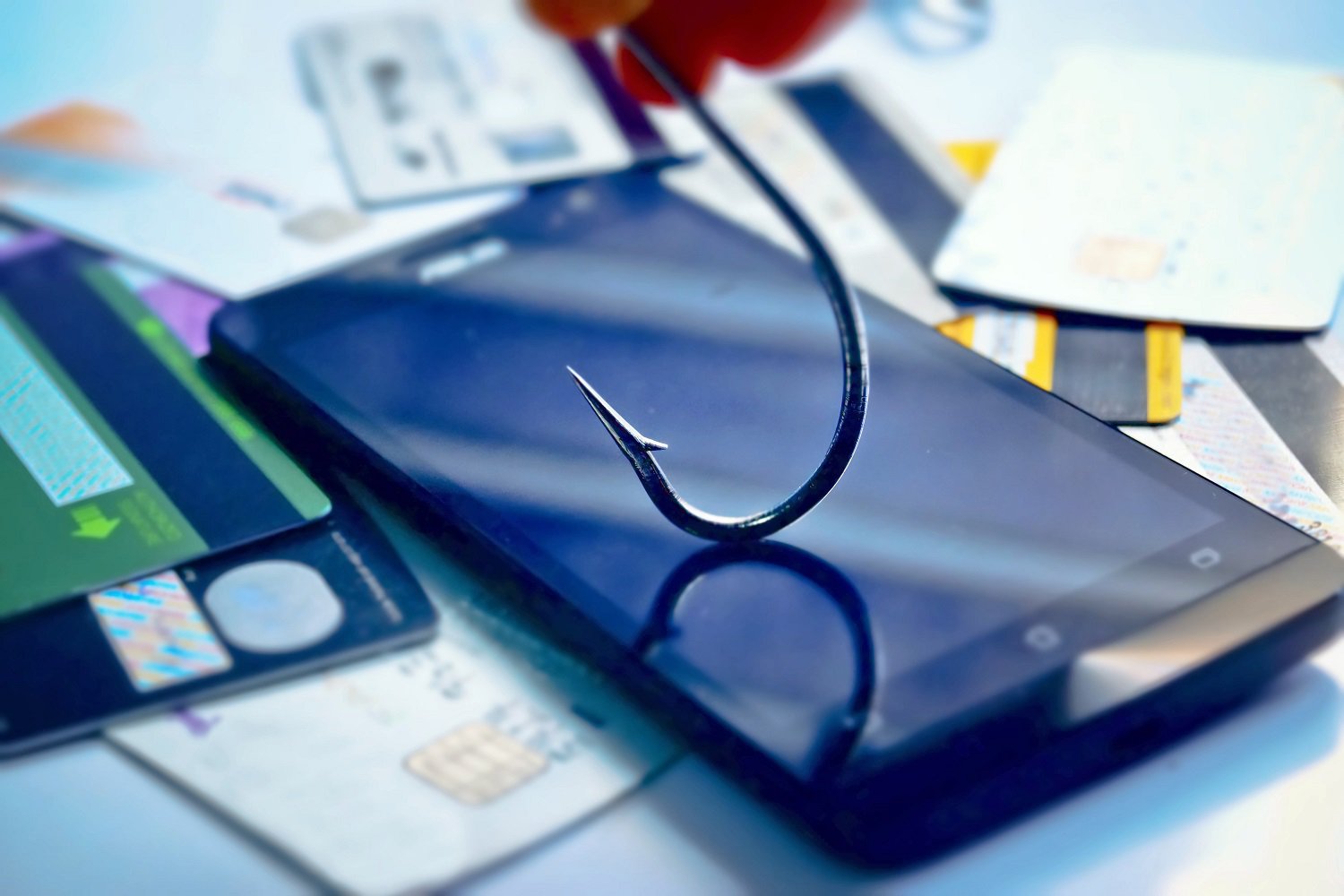 Vishaak boven een smartphone tussen betaalpassen, die digitale fraude en phishing bij online en mobiele betalingen verbeeldt.