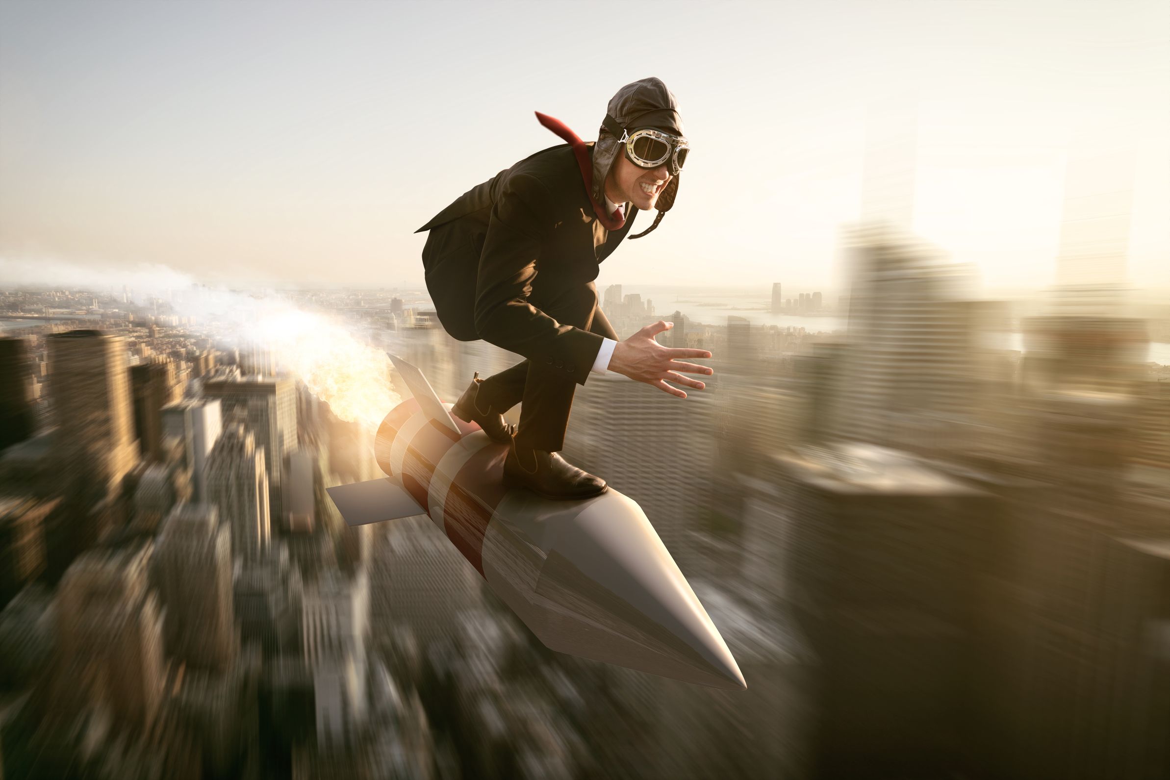Man in pak met pilotenbril balanceert op een raket die met vaart over een stad vliegt, wat snelheid en vooruitgang verbeeldt.