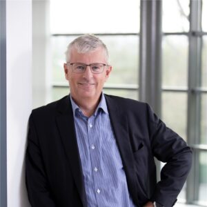 Paul Scholten, CEO van Buckaroo, staat ontspannen met één hand in de zij en kijkt vriendelijk in de camera in een lichte kantooromgeving.