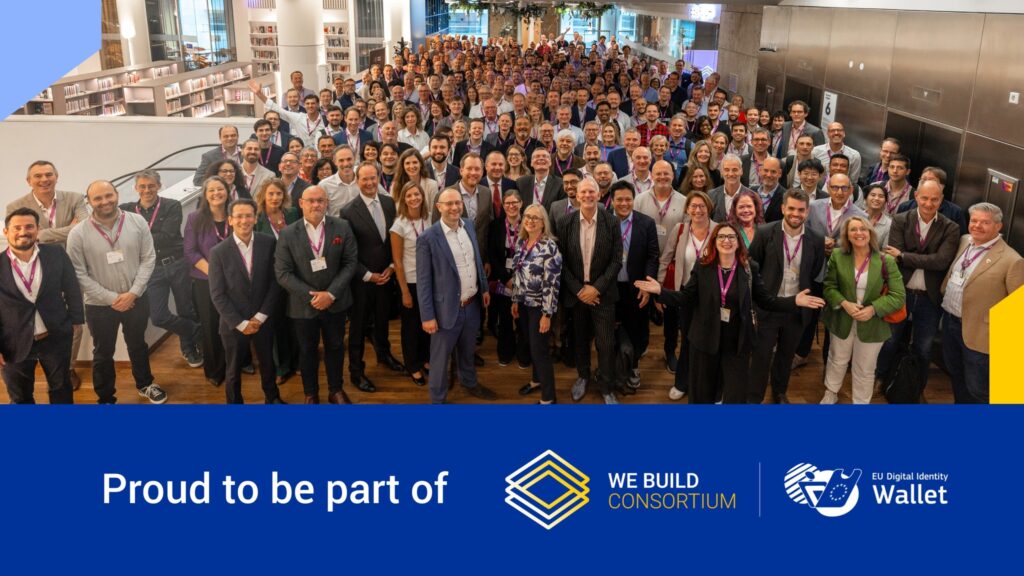 Groepsfoto van grote internationale projectgroep met naambadges, boven tekst over deelname aan het WE BUILD Consortium en de EU Digital Identity Wallet.
