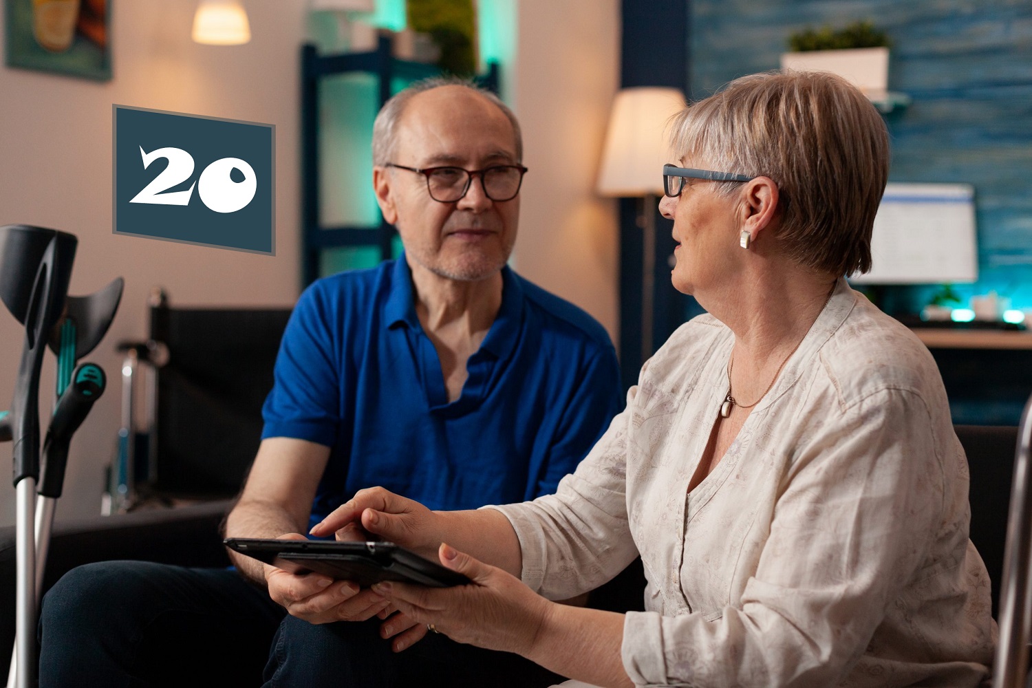 Ouder stel zit in een gezellige woonkamer en bespreekt samen iets op een tablet, als ondersteuning bij digitale bankzaken.