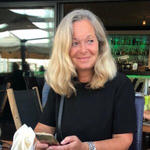 Joyce van der Est, directeur Bankieren bij de Volksbank, houdt een smartphone vast en kijkt ontspannen opzij in een informele horecagelegenheid.